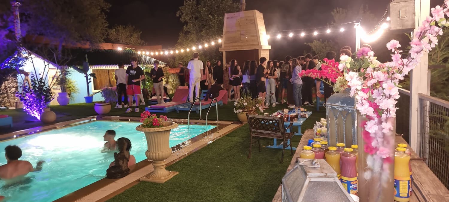 Young adults enjoying a vibrant nighttime pool party at Kaya's Resort, an outdoor event venue near Beit Chabab, with guests swimming and mingling under string lights.
